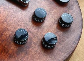 Four potentiometers on a brown guitar body